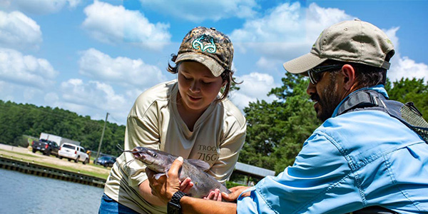 Two volunteers examine a fish that has just been caught at a fishing landing