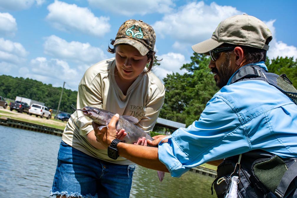 a fishing volunteer helps participant with fish hook removal