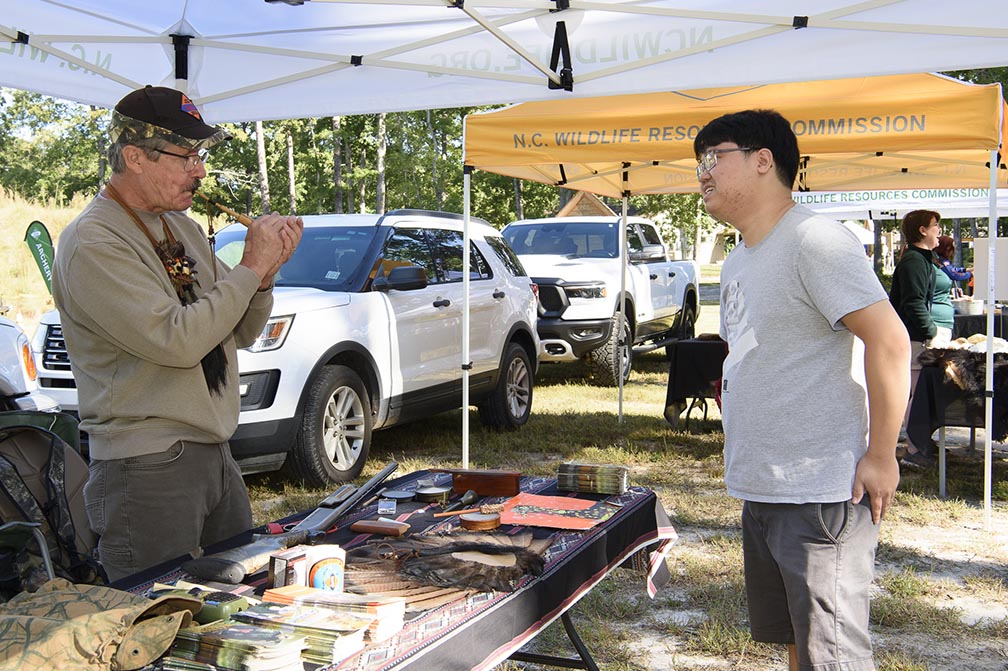 a hunter ed volunteer helps expo participant with turkey call