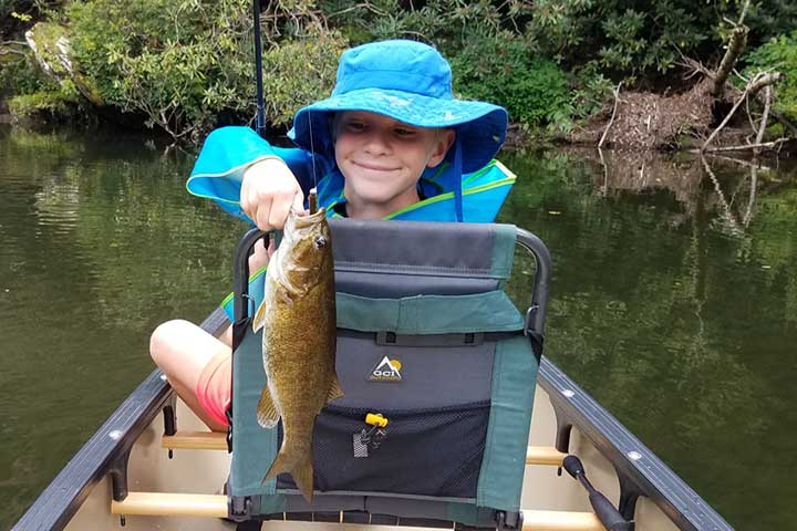 a child in a boat holding a smallmouth bass